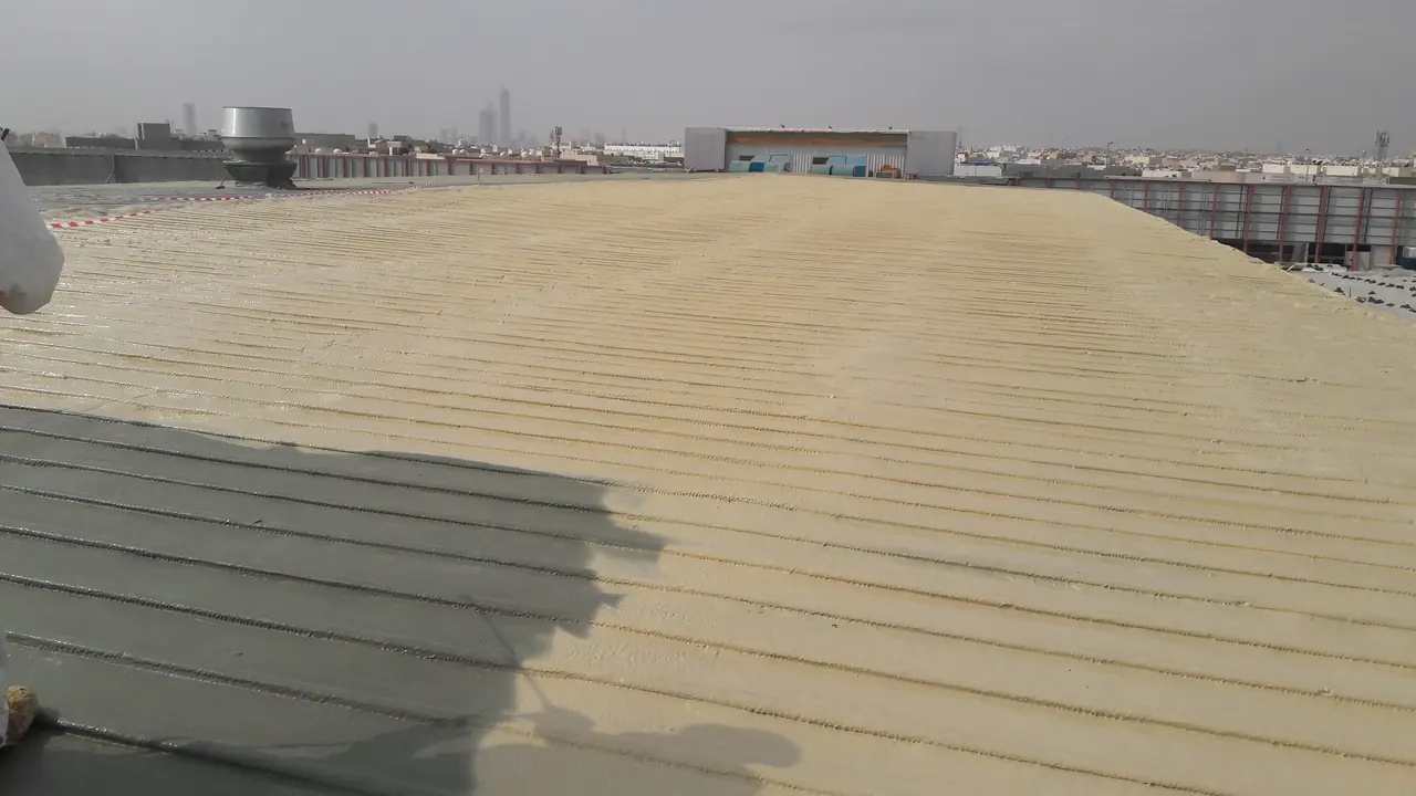 سقف معدني في مول الرياض أثناء تغطيته بطبقة عزل مرشوشة تغطي جزءاً من السطح
